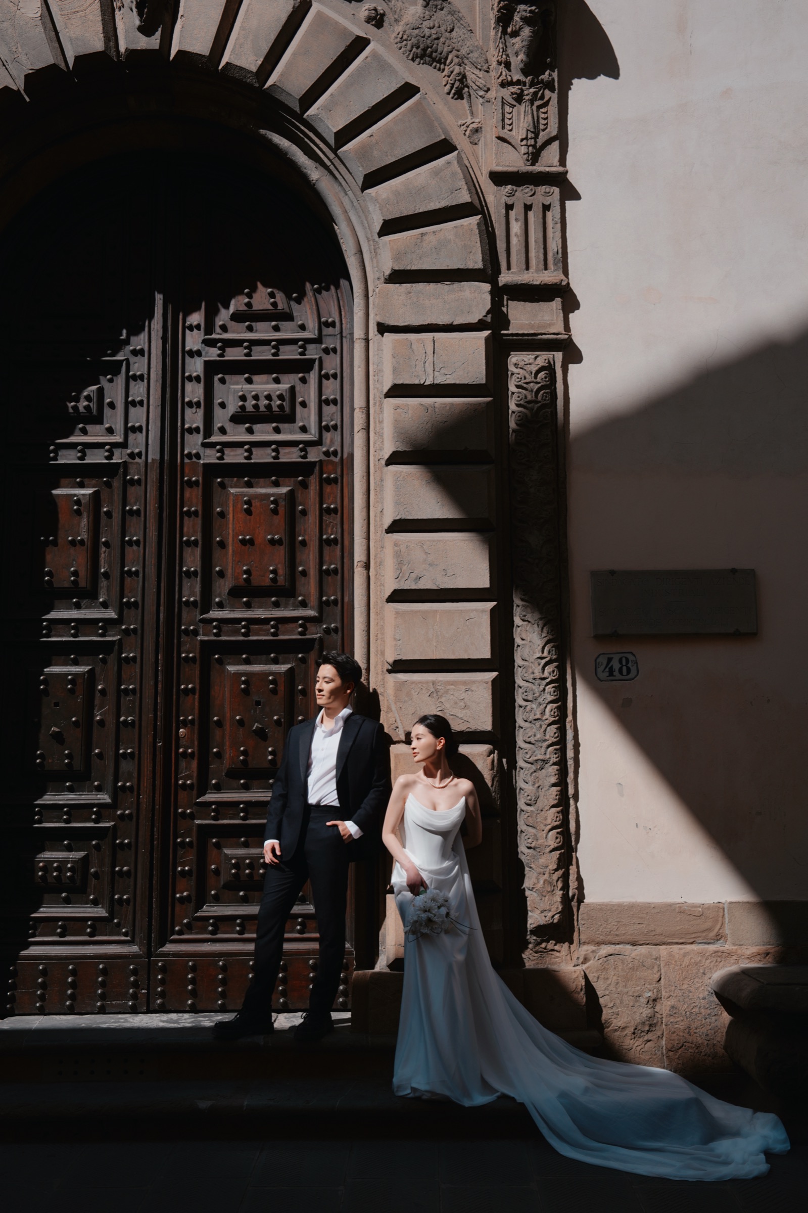 Yue and Andrew standing in the shadow of a carved stone archway in Florence